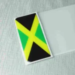 Jamaica flag number plate badge with yellow cross and green and black design.