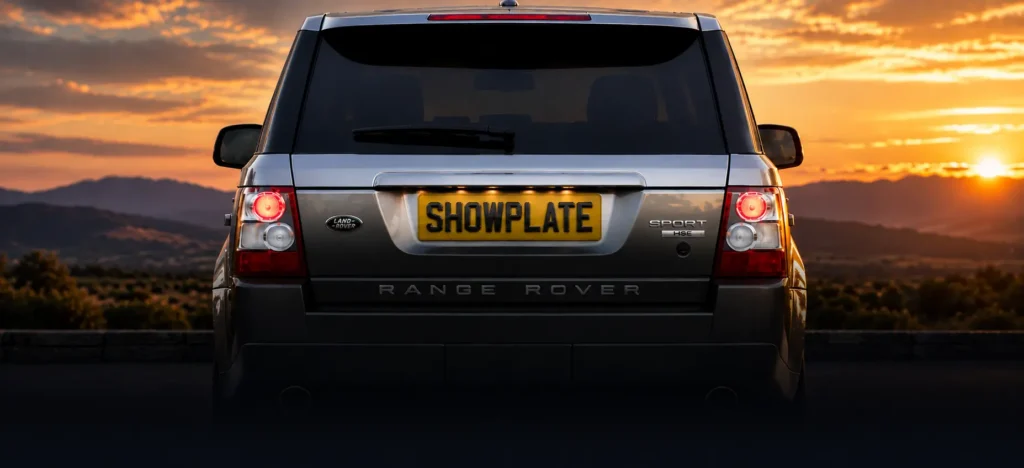 Rear view of a luxury silver Range Rover Sport featuring a custom tinted SHOWPLATE number plate with raised black 4D lettering, photographed against a dramatic sunset.